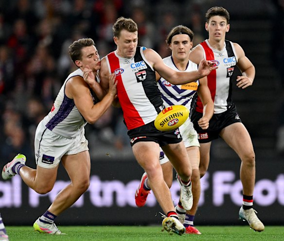 Jack Macrae of the Saints kicks whilst being tackled by Caleb Serong of the Dockers.