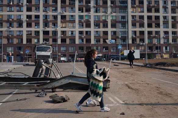 A woman walks past a residential area damaged by strike that hit a shopping centre in Kyiv.