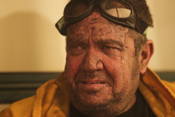 A Bumbalong resident takes a brief respite from defending his property as a bushfire burning south of Canberra threatens  communities in Bumbalong.