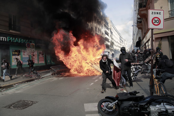 Demonstrators walk with a banner next to garbage and materials that was put on fire during a May Day protest.