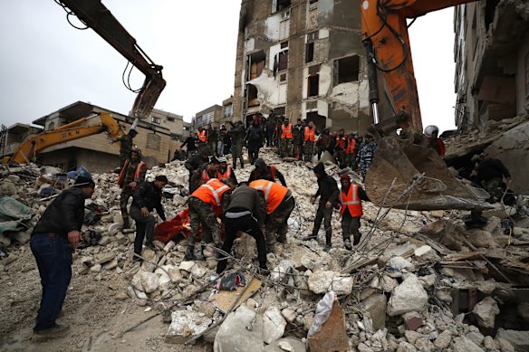 Civil defence workers and security forces search through the wreckage of collapsed buildings in Hama, Syria.