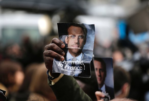 Supporters of French independent centrist presidential candidate, Emmanuel Macron hold up his photo outside his campaign headquarters in Paris.