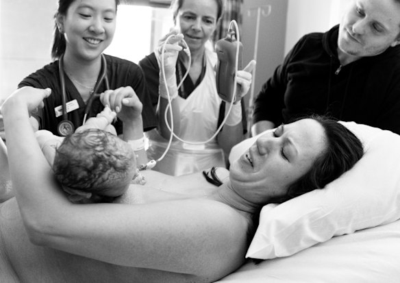This is the moment Lea Fenton and Michael Box get their baby, Caleb, back from Dr Joyce Tan, left, and midwife, Veronica Hegedus after he was quickly checked out because his heart rate dropped during the delivery, at the Royal Hospital for Women in Randwick, Sydney. 