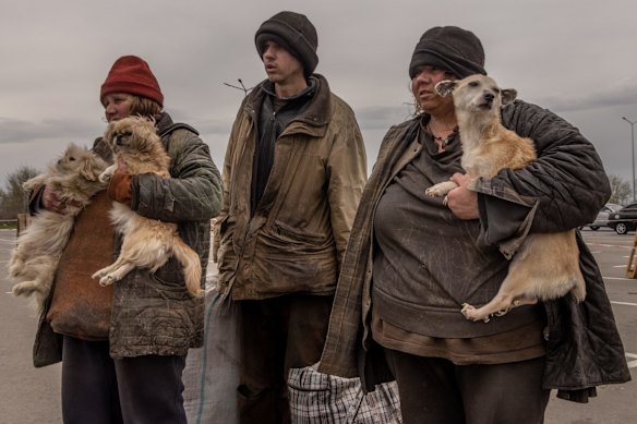 A family from Myrne, a town currently occupied by Russian forces, wait to register with police at an evacuation point for people fleeing towns under Russian control, in Zaporizhzhia.