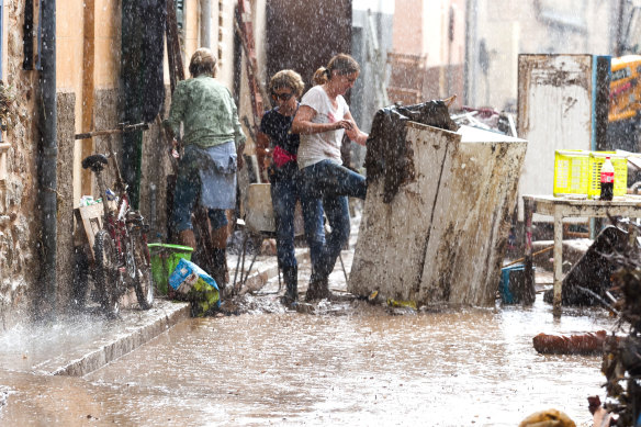 Residents place their damaged belongings on the street under pouring rain.