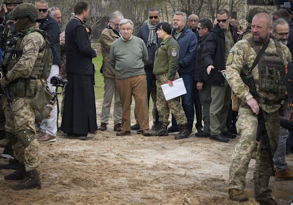 UN Secretary-General Antonio Guterres, centre, stands on the side of a mass grave in Bucha.