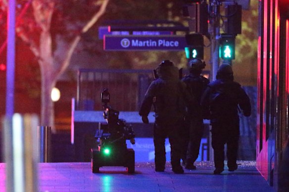 The bomb squad enter the Lindt Chocolat Cafe in Martin Place next to a robot.