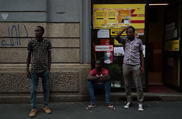 Mohamed Ahmed (left) 23, Adam Abkar Mohamed 20 (centre) and Mohamed Ahmed 23 (right) from Darfur in Sudan check to see if their money has been wired to the western union outlet in Milan so that they can proceed to another country.