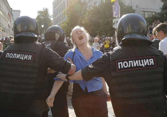Police officers detain a woman during an unsanctioned rally.