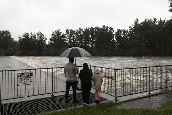 People watch as the Nepean River rages at the Penrith weir.