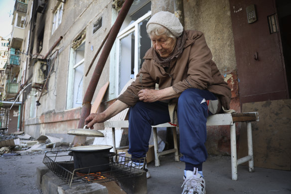 A woman cooks in the yard of her damaged apartment building in Mariupol.
