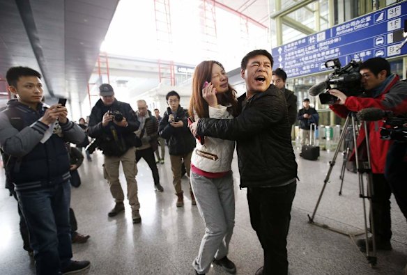 A relative (woman in white) of a passenger onboard Malaysia Airlines flight MH370 cries as she talks on her mobile phone at the Beijing Capital International Airport in Beijing.