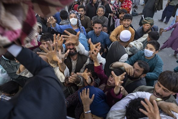 Displaced Afghans reach out for aid from a local Muslim organization at a makeshift IDP camp on August 10, 2021 in Kabul, Afghanistan. People displaced by the Taliban advancing are flooding into the Kabul capital to escape the Taliban takeover of their provinces.