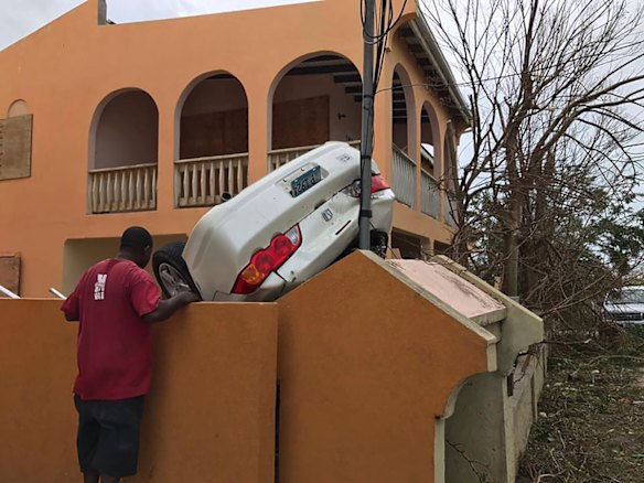 A man looks at a vehicle turned upside down by winds brought on by Hurricane Irma in the British overseas territory of Anguilla. 