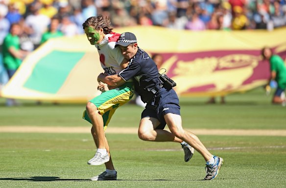 A man who invaded the pitch before the match began is tackled by police.
