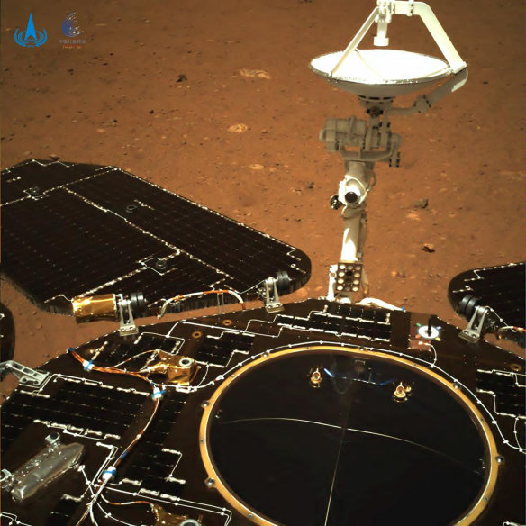 In this photo taken by China’s Zhurong Mars rover, the rover’s solar panels and antenna are deployed as the rover sits on its lander on the surface of Mars. 