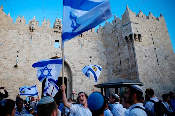  Israelis wave national flags outside the Old City's Damascus Gate, in Jerusalem.