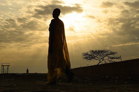 A woman wearing gumboots walks along a path inside the UN Bentiu Protection of Civilian's site where over 100,000 people live having fled violence and fighting.