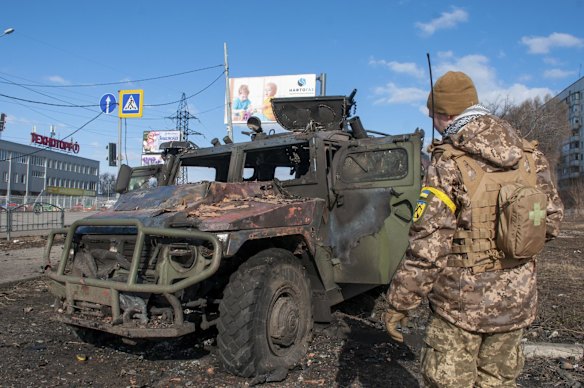 A Ukrainian soldier inspects a damaged military vehicle after fighting in Kharkiv.