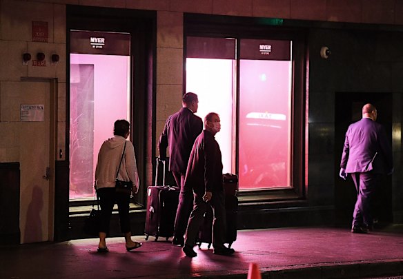 A couple are escorted towards a taxi after leaving quarantine at the Swissotel on Market street in Sydney CBD. April 8, 2020