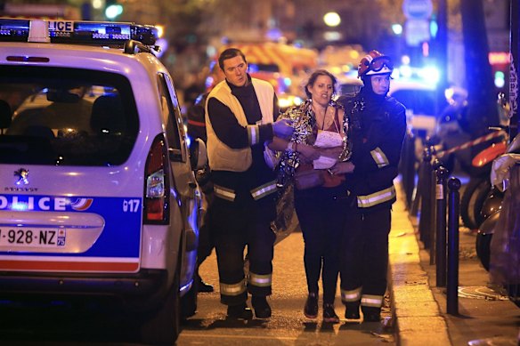 Rescue workers help a woman after a shooting, outside the Bataclan theater in Paris.