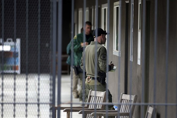 Investigators talk to tenants at an apartment building where a gunman killed three people during Friday night's mass shooting.