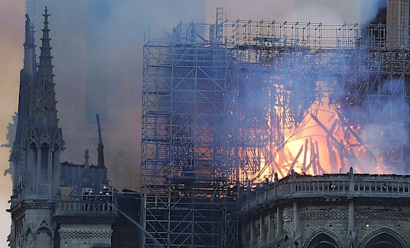 Firefighters tackle the blaze as flames and smoke rise from Notre Dame cathedral. Massive plumes of yellow brown smoke is filling the air above Notre Dame Cathedral and ash is falling on tourists and others around the island that marks the center of Paris.