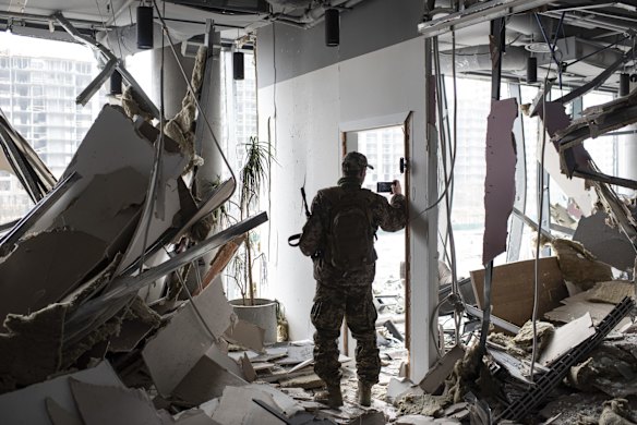 A soldier takes pictures inside the destroyed Retroville trade center in Kyiv.