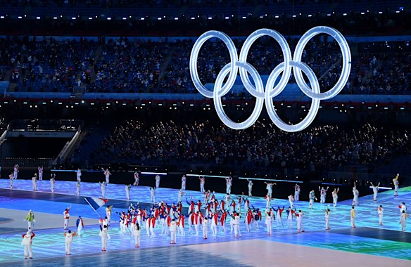 Flag bearers Kevin Rolland and Tessa Worley of Team France lead the team under the Olympic rings.