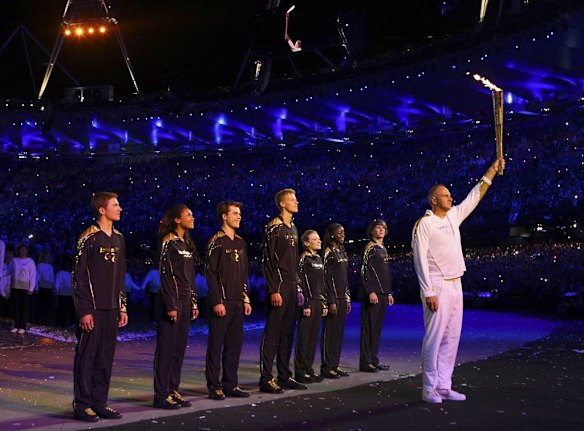 Steve Redgrave holds the Olympic flame aloft before he passes it to the seven final torchbearers.