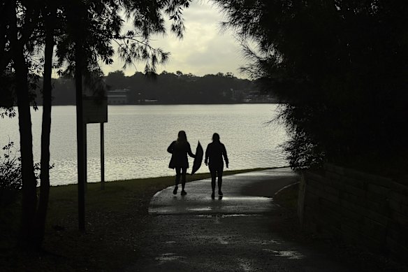 People walk along a track past Iron Cove on the Bay Run on day two of the Sydney lockdown in Lilyfield.
