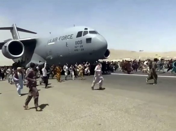 Hundreds of people run alongside a U.S. Air Force C-17 transport plane as it moves down a runway of the international airport, in Kabul, Afghanistan. Thousands of Afghans have rushed onto the tarmac at the airport, some so desperate to escape the Taliban capture of their country that they held onto the American military jet as it took off.