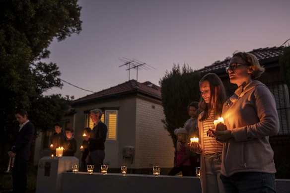 Penny Keane and her Mother, Laura Buzo observe a minute silence, while keeping social distance at a driveway dawn service for ANZAC Day.