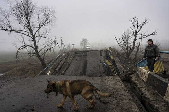 Sasha, 50, waits for his dog Druzhok before crossing a bridge destroyed by the Russian army when it retreated from villages in the outskirts of Kyiv.