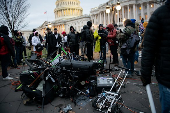 Demonstrators stand next to destroyed TV broadcast equipment belonging to journalists.