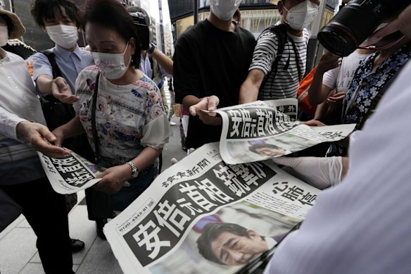An employee distributes extra editions of the Yomiuri Shimbun newspaper reporting on the shooting.