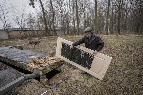 A man lifts a door covering the opening of an underground concrete enclosure in which bodies of civilians killed by Russian forces, according to residents, were dumped as people were unable to transport them to a cemetery in Bucha.