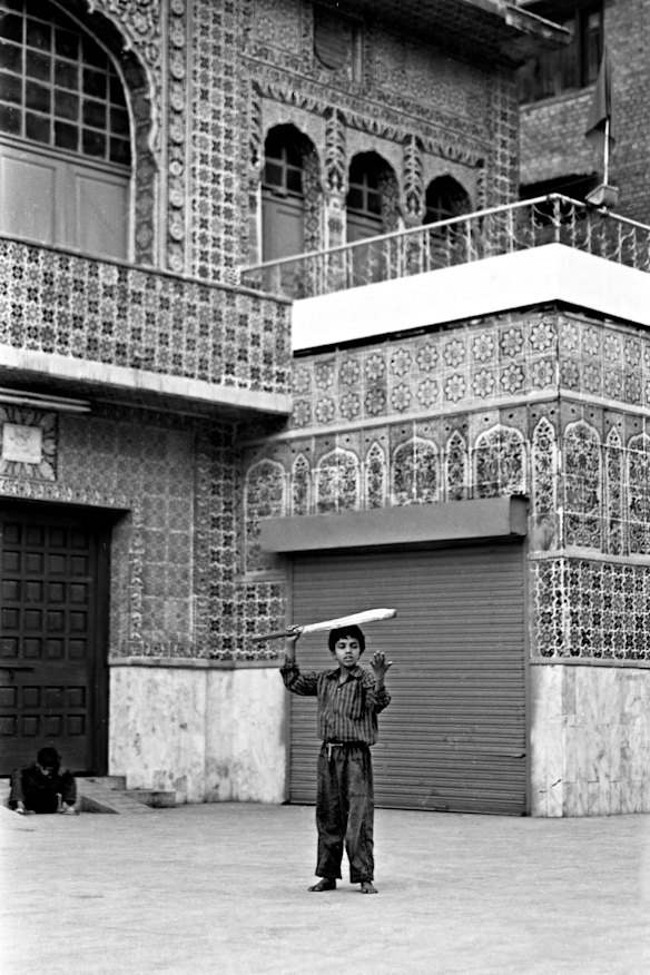 Boy with cricket bat and ball at a mosque in Lahore.