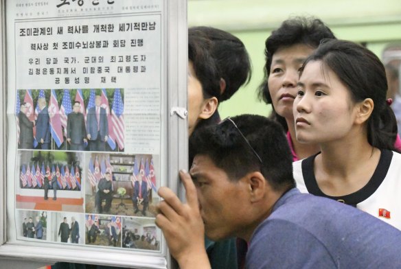 People look at the display of local newspaper reporting the Trump-Kim meeting at a subway station in Pyongyang.