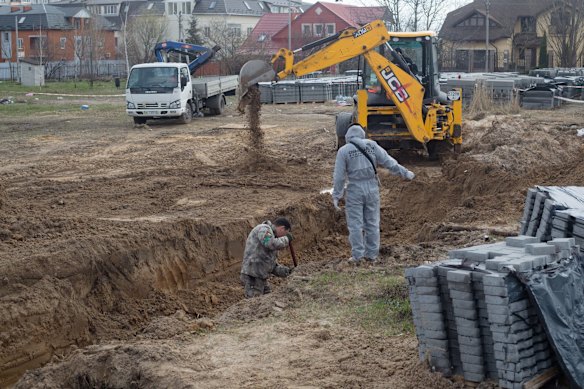 Workers unearth a mass grave in Bucha.