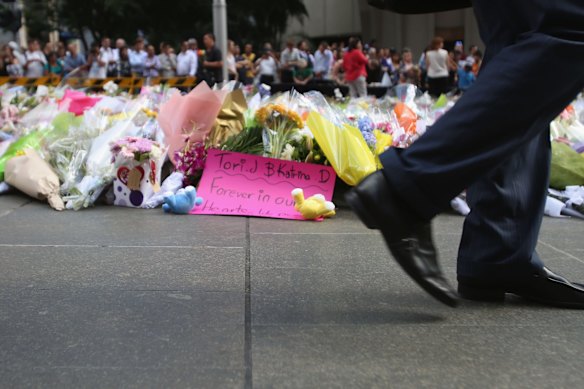 A sign that Reads "Tori J and Katrina D, forever in our hearts..." is left with toys and flowers at Martin Place.
