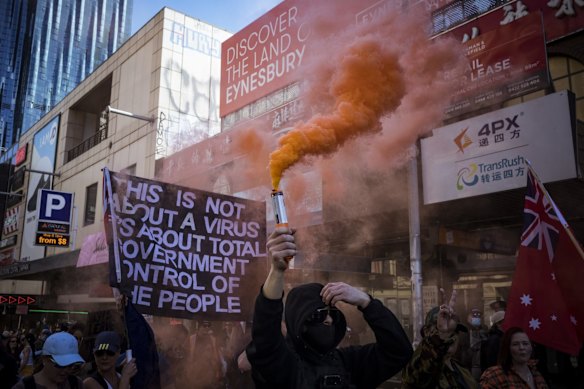 A protester sets off a flare as the pack of thousands snakes through Melbourne’s CBD.