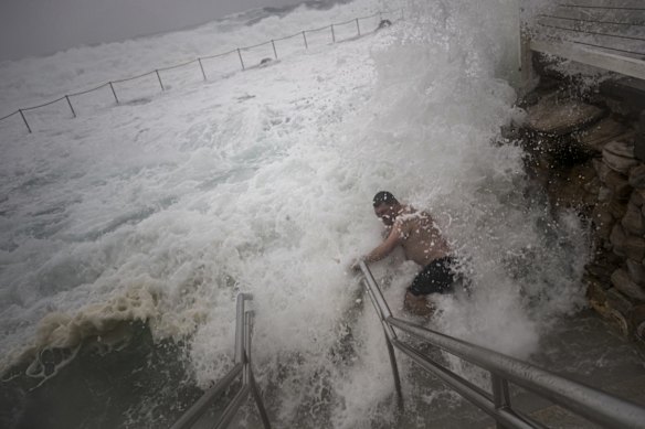 Wild weather at Bronte as a swimmer tries to enter the ocean pool.