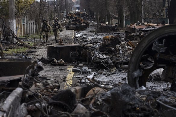 Soldiers walk through the remains of destroyed Russian tanks in Bucha.