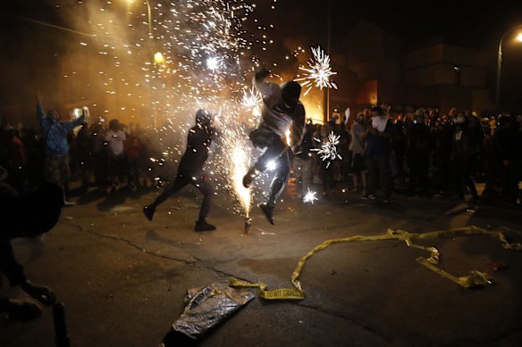 Protesters set off fireworks as a fire burns at the Minneapolis police 3rd Precinct building.