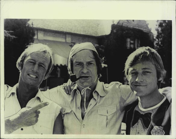 Paul Hogan and "Strop" (John Cornell) in Hollywood with Hugh Hefner, who wears 'Strop's" lifesaver's cap. February 26, 1986.