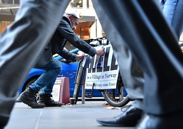 John McKenzie, a pastafarian (satirical religion), who is pasting signs over Jesus bikes in the city