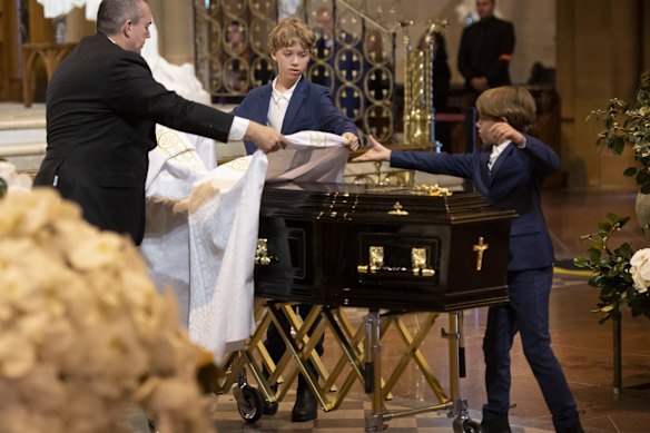 Dorian and Florian Spender McGuinness place the Pall on the casket as family and friends gather for the state funeral of fashion designer Carla Zampatti AC.