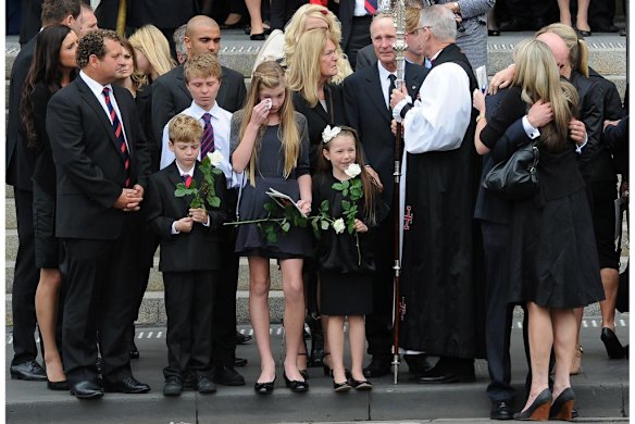 Archbishop  Archbishop Philip Freier  with Brian and Teresa Stynes (parents) after memorial service for Jim Stynes while daughter Matisse wipes a tear with younger brother Tiernan at her side.