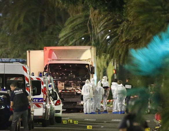 French police forces and forensic officers stand next to a truck that ran into a crowd in Nice.